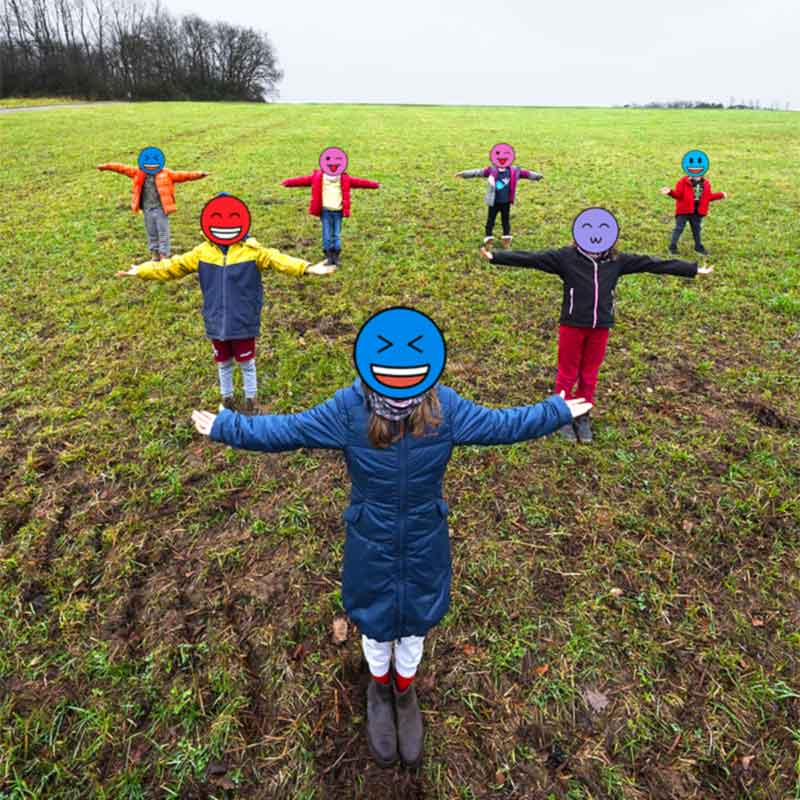 Seven kids on a grassy field forming a tree fractal through forced perspective.